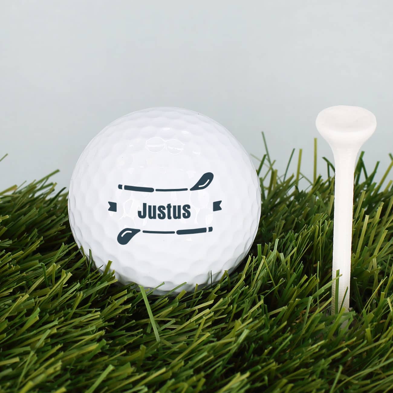 Golfball mit Wunschname und zwei Golfschlägern als Verzierung